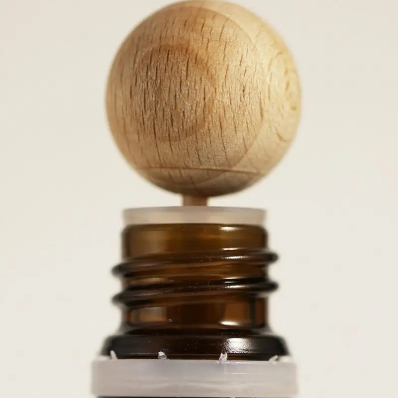 Bouchon diffuseur en bois installé sur un flacon d’huile essentielle